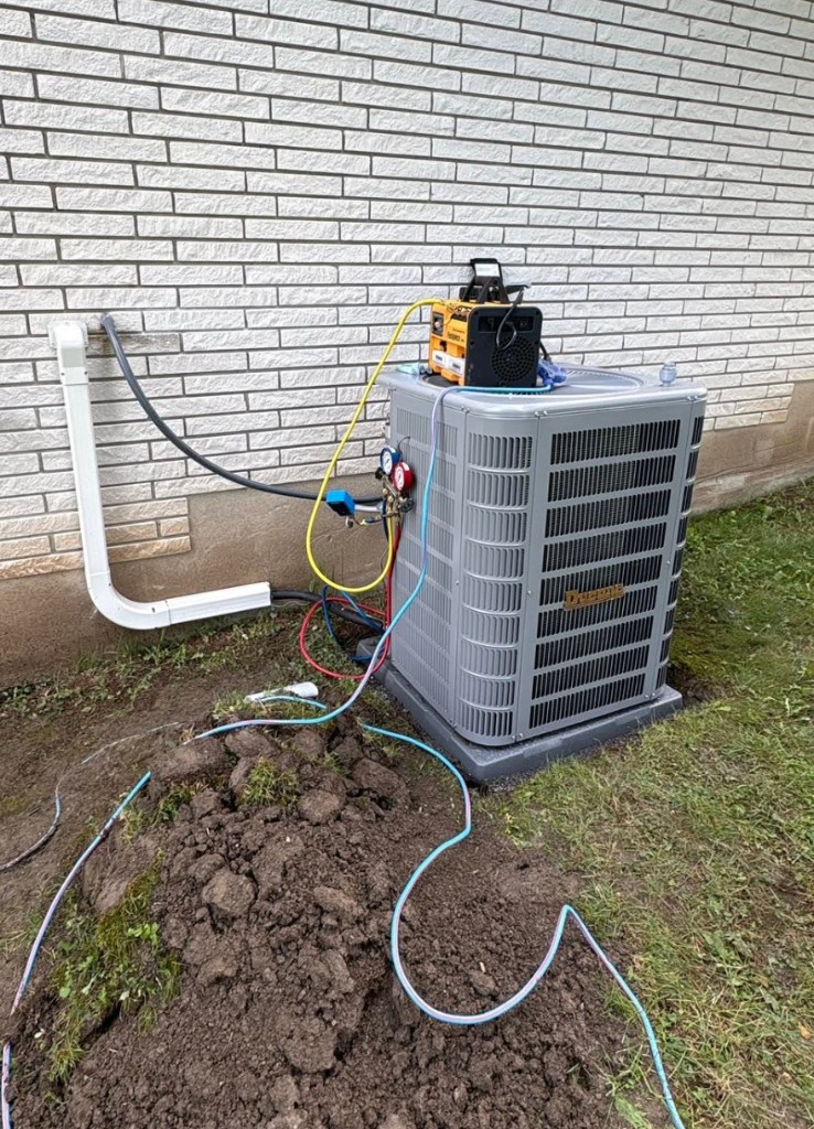 New Ducane condenser on a pad with a vacuum pump, refrigerant lines, and fresh soil