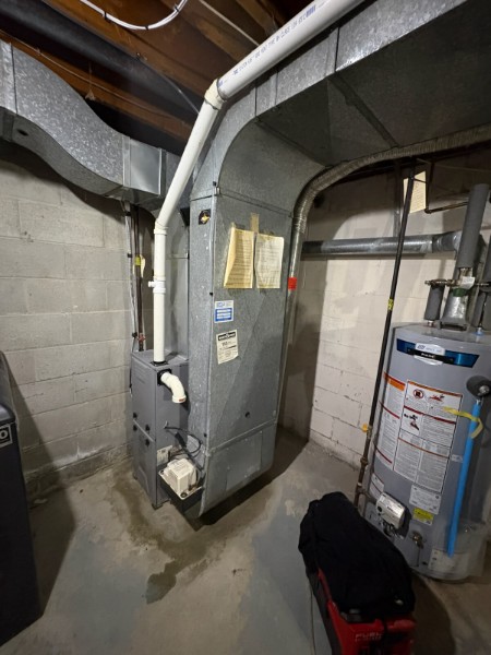 Gray furnace and water heater installed in a basement mechanical room
