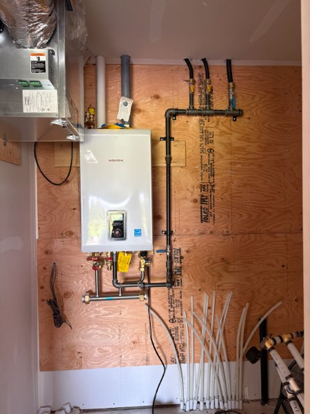 Navien tankless water heater with black iron gas piping and PEX tubing in a mechanical room